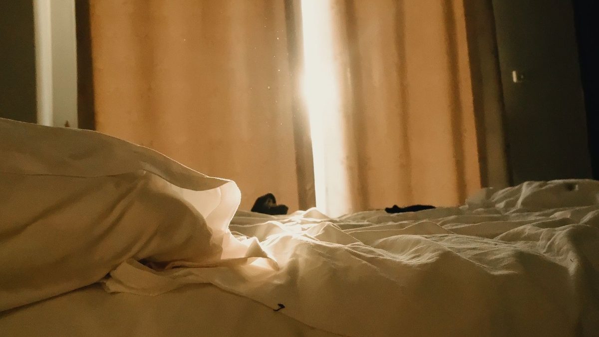 Late sun through a curtain onto an unmade bed